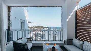 Un balcon avec un canapé, deux fauteuils, une table avec des verres et une vue sur le paysage urbain.