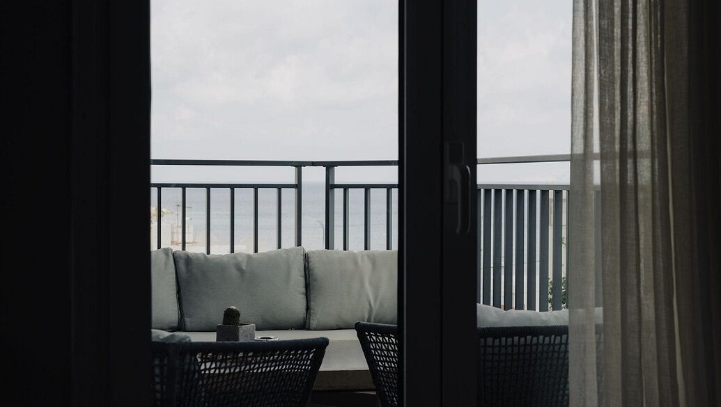 Un balcon doté d’un coin salon avec des coussins, d’une petite table avec une tasse et d’une chaise.