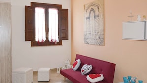 A room with a red sofa, two white cushions, a window with wooden shutters, a white cabinet, and a framed sketch on the wall. - La Casa al Centro (Custonaci)