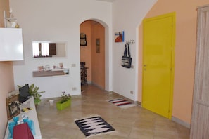 Un pasillo con mostrador de recepción, una puerta amarilla y un espejo en la pared.