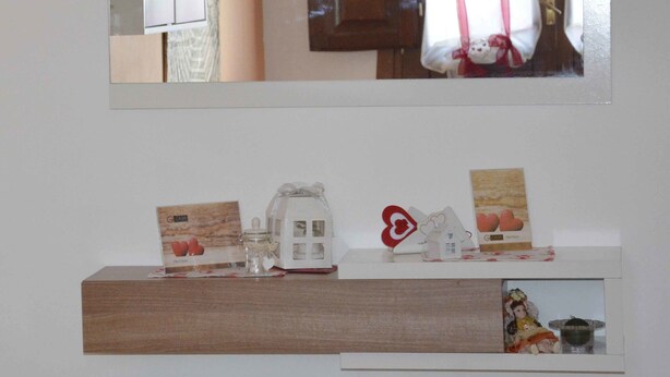 A wall-mounted mirror above a wooden shelf with decorative items. - La Casa al Centro (Custonaci)