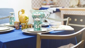Una mesa de comedor dispuesta con diversos platos de cerámica y una jarra, rodeada de sillas.