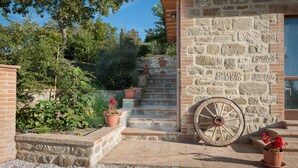 A stone staircase leading up to a building with a large wooden wheel. - Agriturismo Il Beccafico Alpaca (Gubbio)