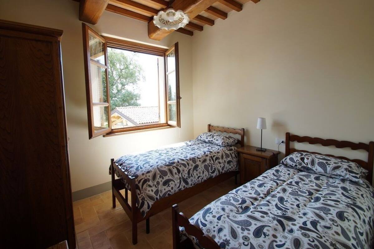 Une chambre avec deux lits, des têtes de lit en bois, une fenêtre avec vue et un ventilateur de plafond.