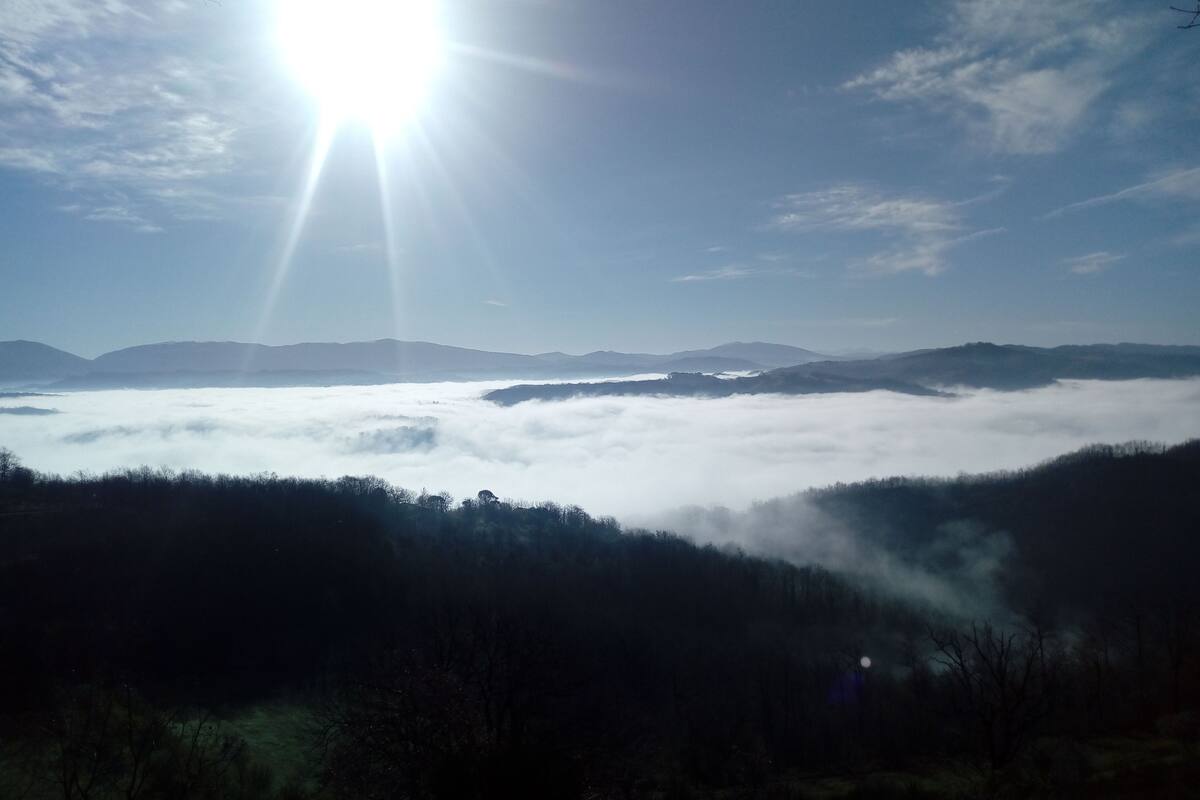 Un paysage avec un ciel ensoleillé, une vallée et des montagnes lointaines.