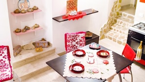 A dining area with a table set for four, surrounded by pink shelves with decorative items. - La Casa Siciliana (Custonaci)