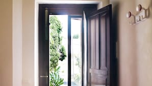An open door leading to a balcony with a view of greenery and a building. - La Casa Siciliana (Custonaci)