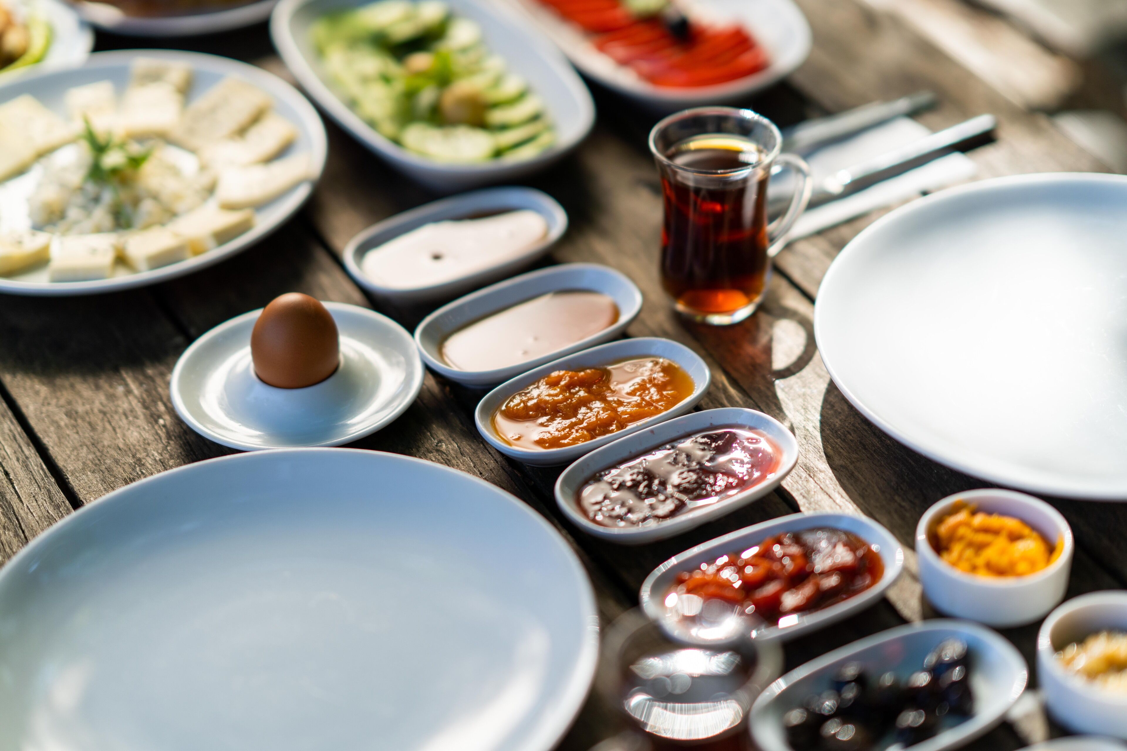 A variety of dishes and condiments on a wooden table, suggesting a meal setting.