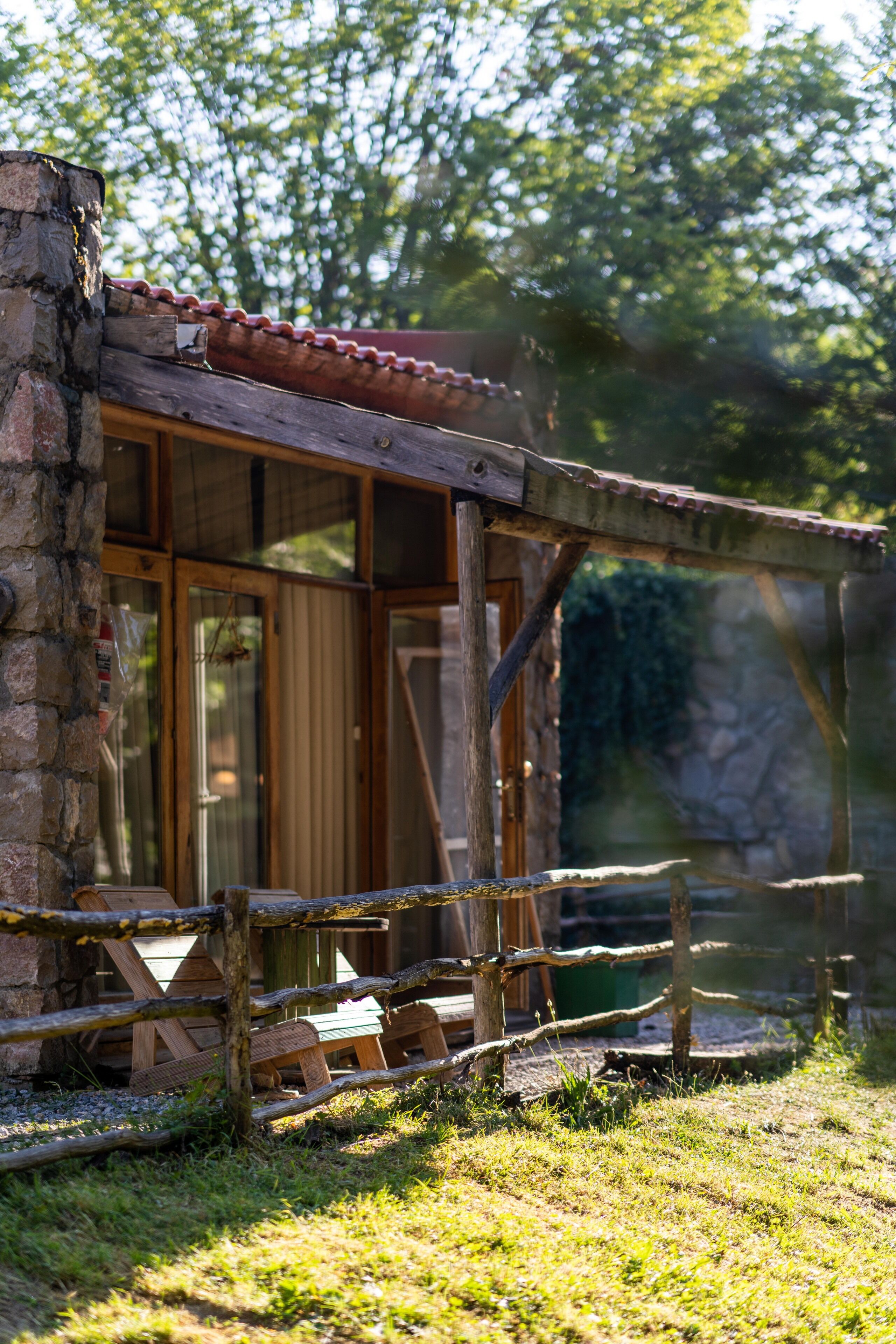 A rustic wooden cabin with a tiled roof, a glass door, and a wooden deck.