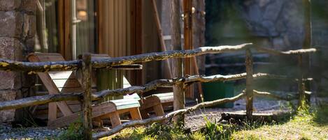 A rustic wooden cabin with a tiled roof, a glass door, and a wooden deck.