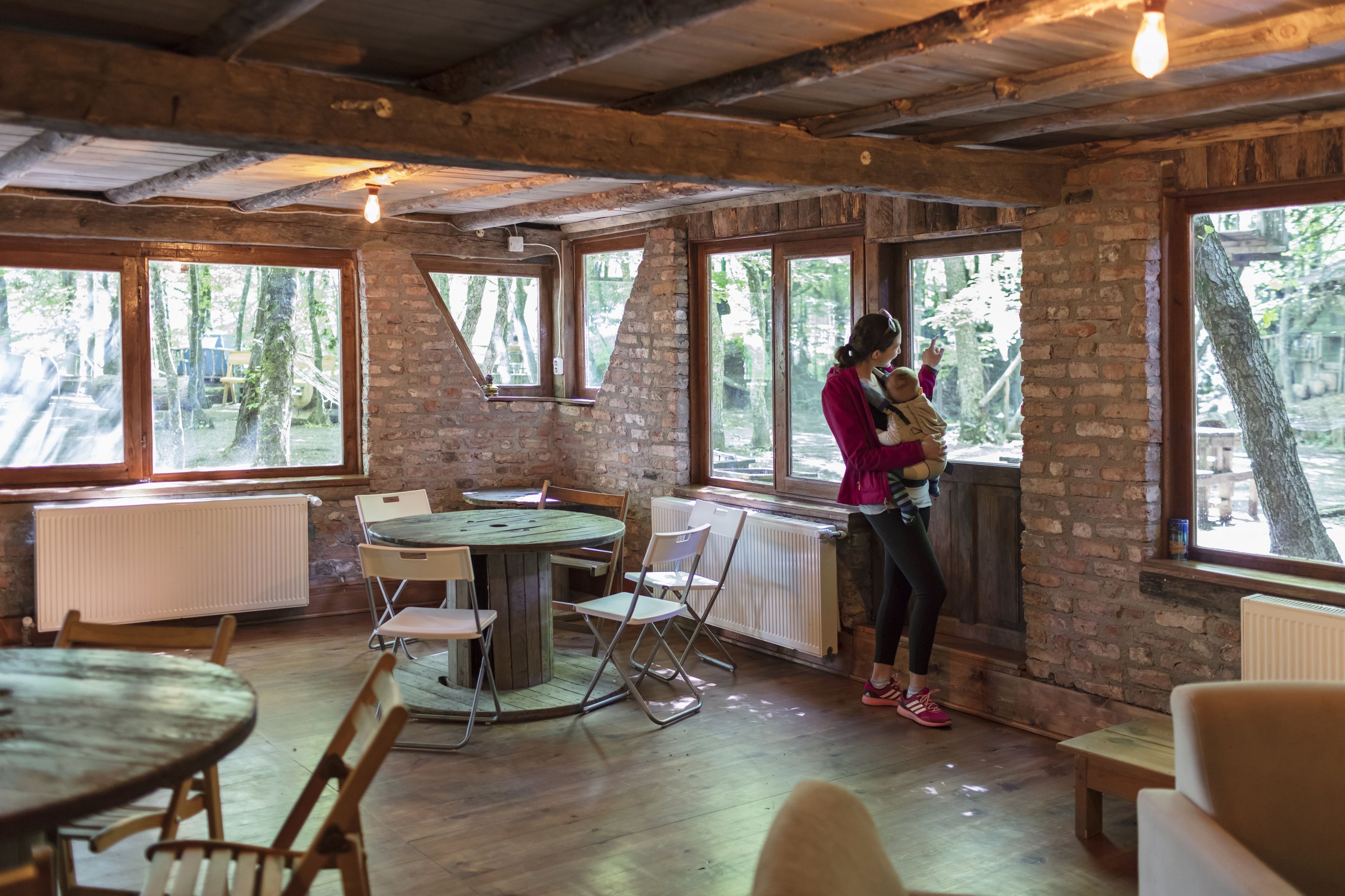 A rustic room with large windows, a round table, and folding chairs.
