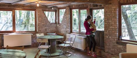 A rustic room with large windows, a round table, and folding chairs.