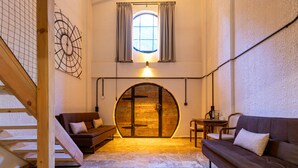A cozy room with a wooden door, a wooden staircase, a brown sofa, and a small table with a lamp. - Hindiba Doga Evi (Mengen)