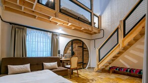 A bedroom with a loft area, a wooden staircase, and a cozy seating area. - Hindiba Doga Evi (Mengen)