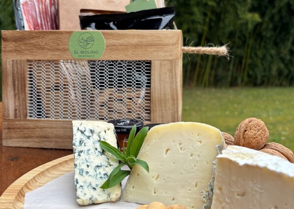 A wooden cheese board with various cheeses and nuts, a bottle of wine, and a green plant.