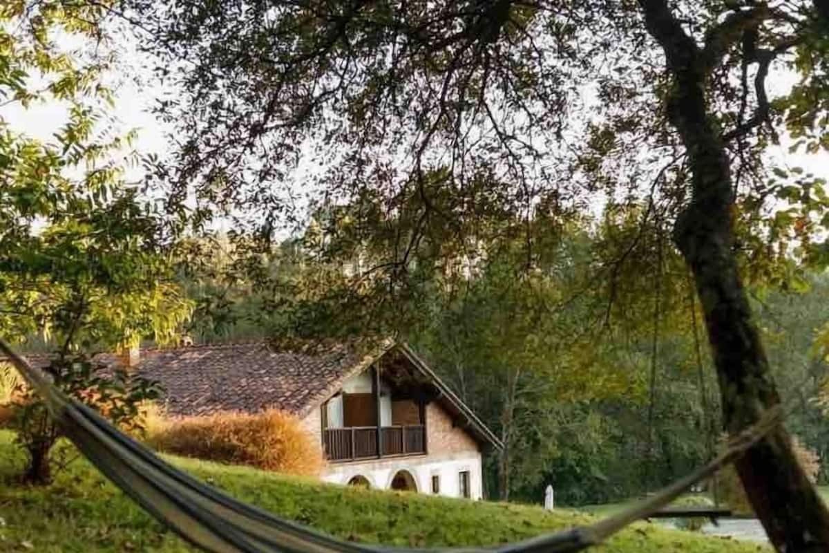 A house with a sloped roof, surrounded by trees and grass.