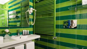 Un baño con paredes de azulejos verdes, un lavamanos blanco y un perchero para toallas.