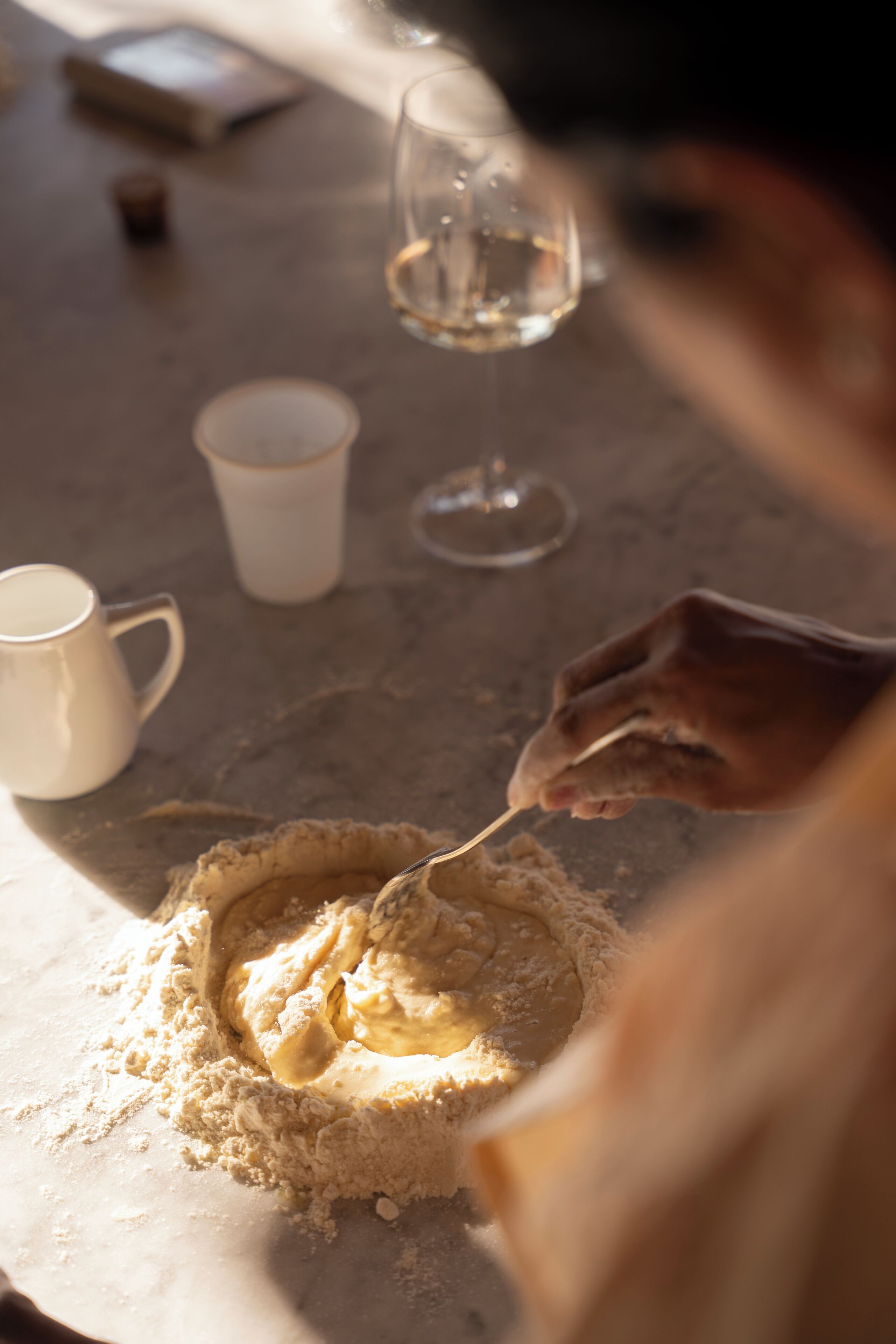 Gros plan d’une main mélangeant une substance crémeuse dans un bol posé sur une table.