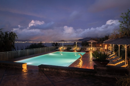 Una piscina al aire libre, sombrillas, sillones reclinables de piscina