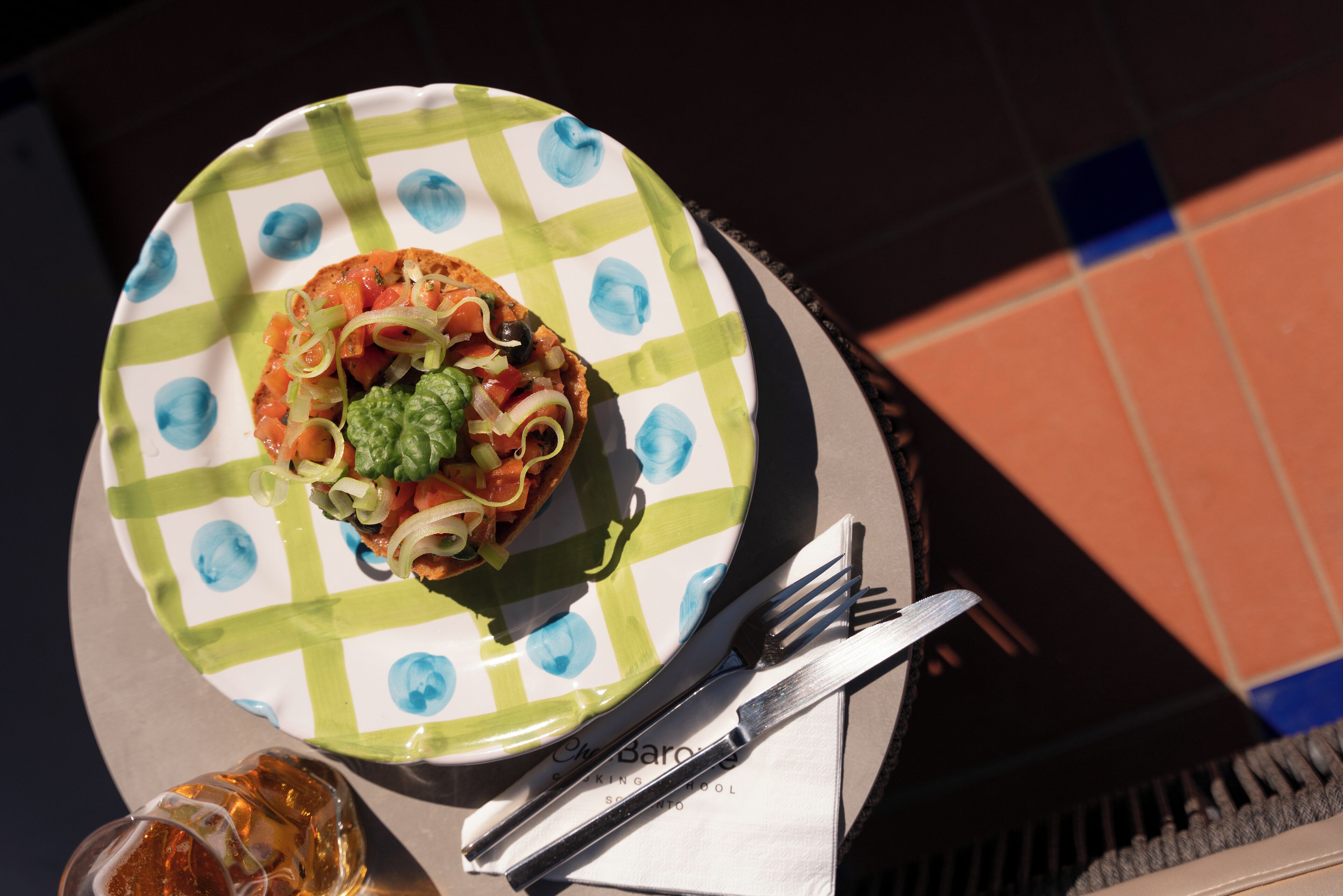 A plate of food with a green and white checkered tablecloth, a fork, and a knife on a table.