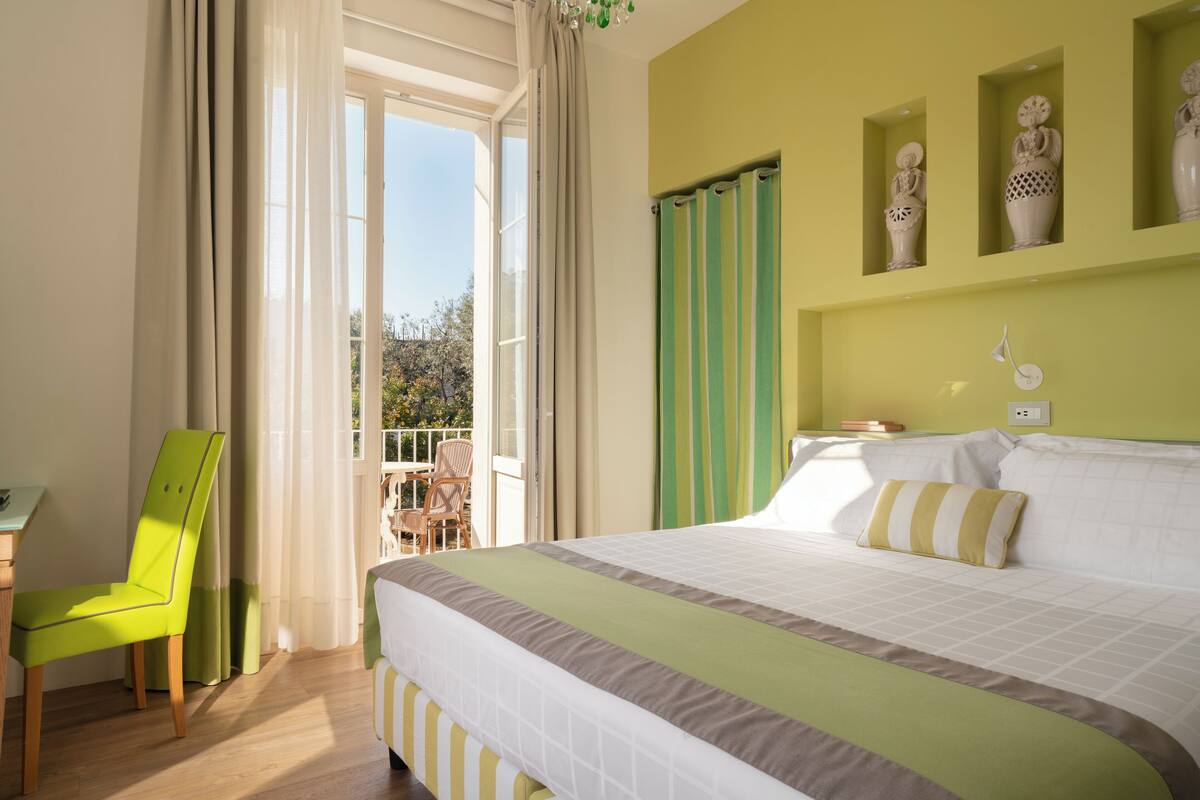 Une chambre d’hôtel avec un lit, une chaise, un balcon et des vases décoratifs accrochés au mur.