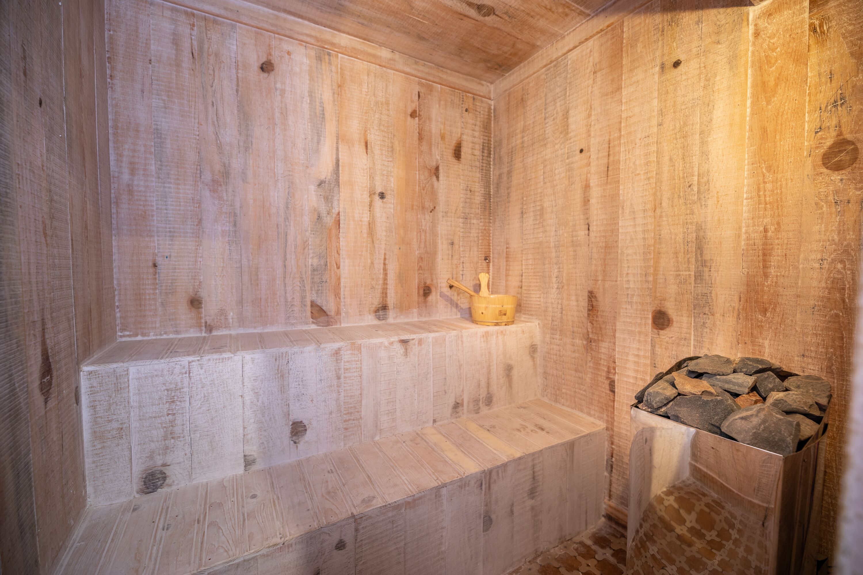A wooden sauna with benches and a stone basin.