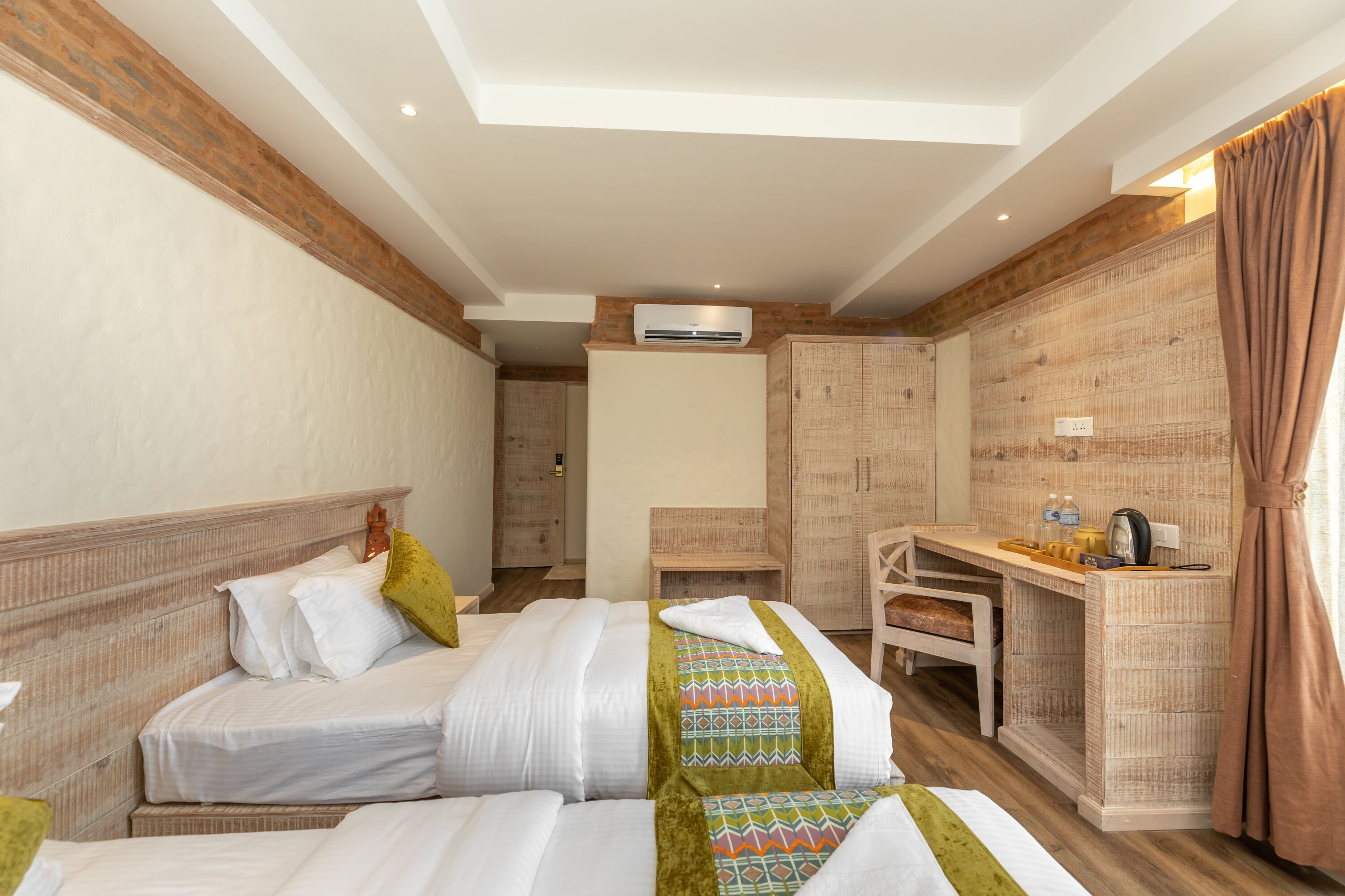 A hotel room with two beds, a desk, and a wardrobe.
