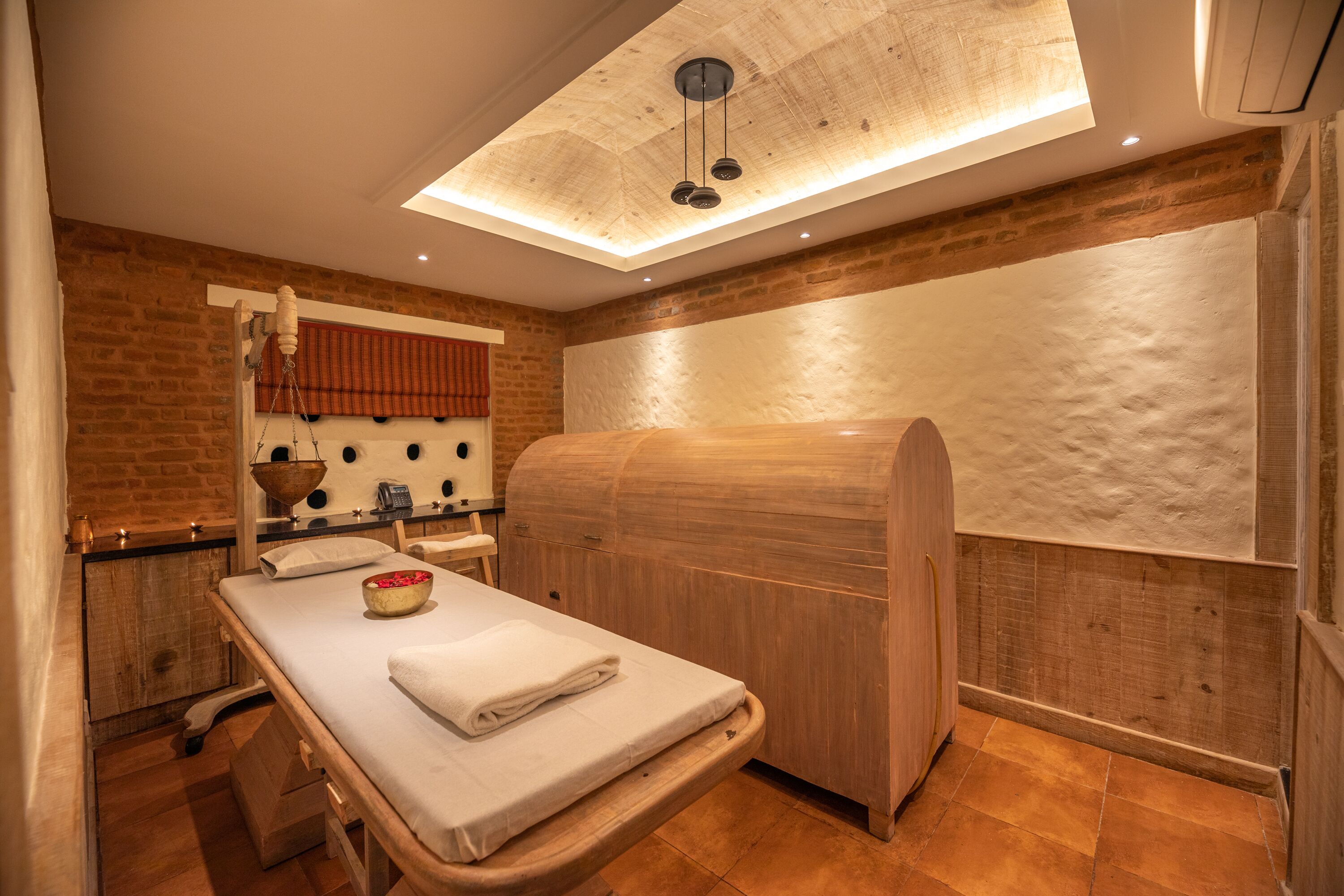 Une salle de spa équipée d’une table de massage en bois, d’un meuble en bois et d’un grand miroir.