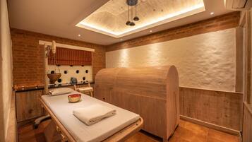 A spa room with a wooden massage table, a wooden cabinet, and a large mirror.