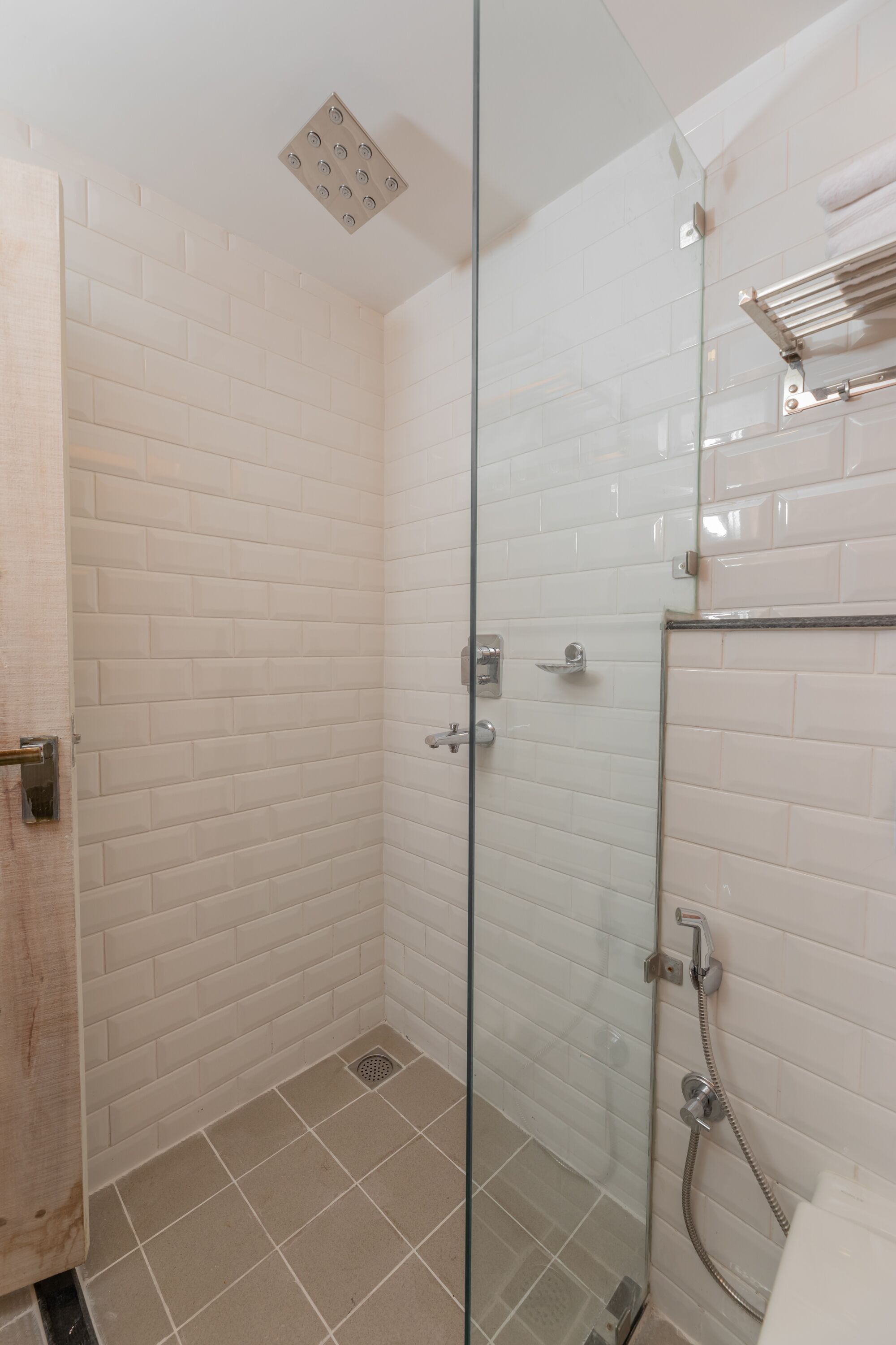 A glass-enclosed shower with white tiled walls and a metal showerhead.