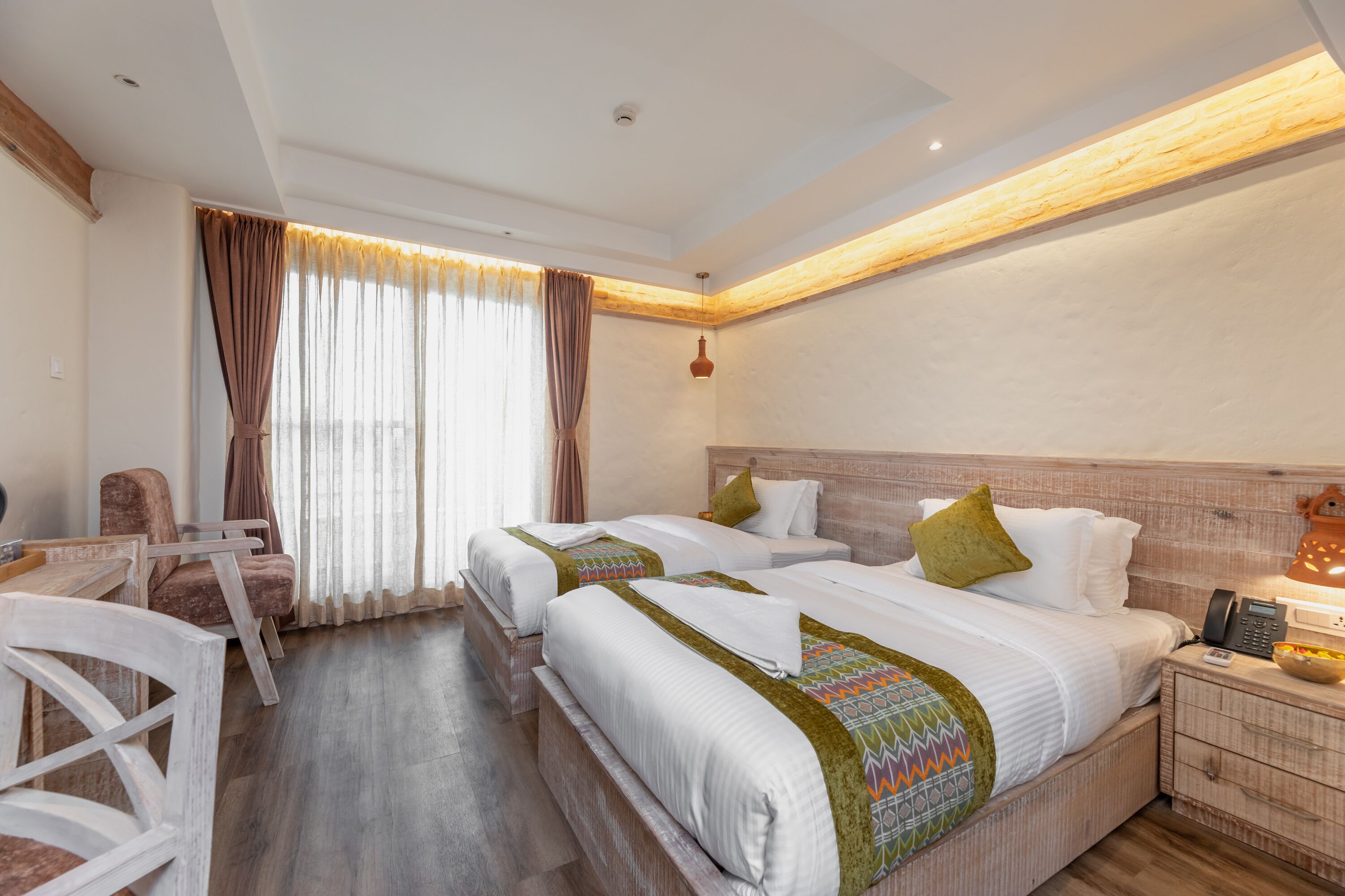 A hotel room with two beds, a desk, and a chair.