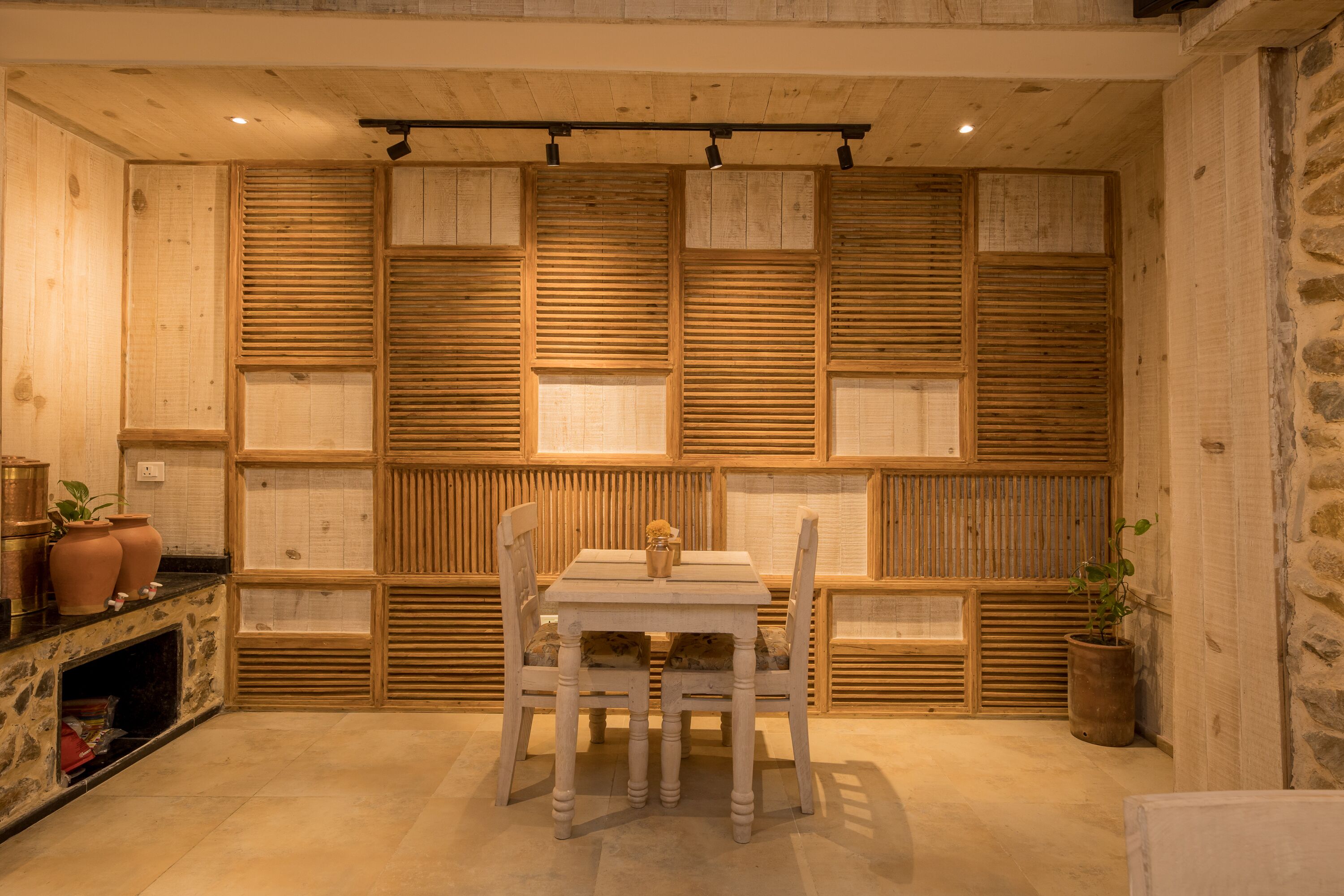 A dining area with a wooden table and chairs, a stone wall, and a fireplace.