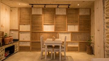 A dining area with a wooden table and chairs, a stone wall, and a fireplace.