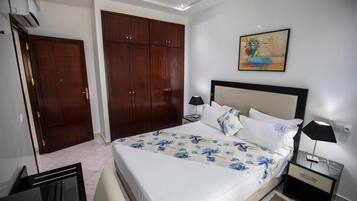 Une chambre à coucher avec un grand lit, une armoire, une table de chevet et un tableau au mur.