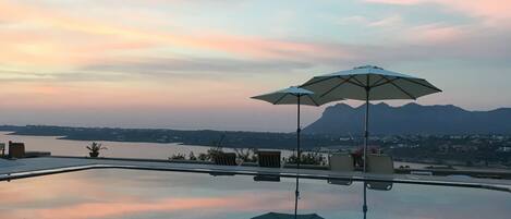 En sÀsongsöppen utomhuspool, parasoller och solstolar