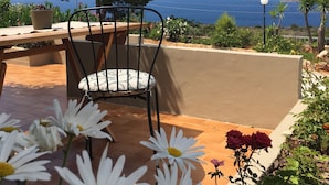 A patio with a chair, a potted plant, and a view of the sea. - Theodosia Studios (Chania)