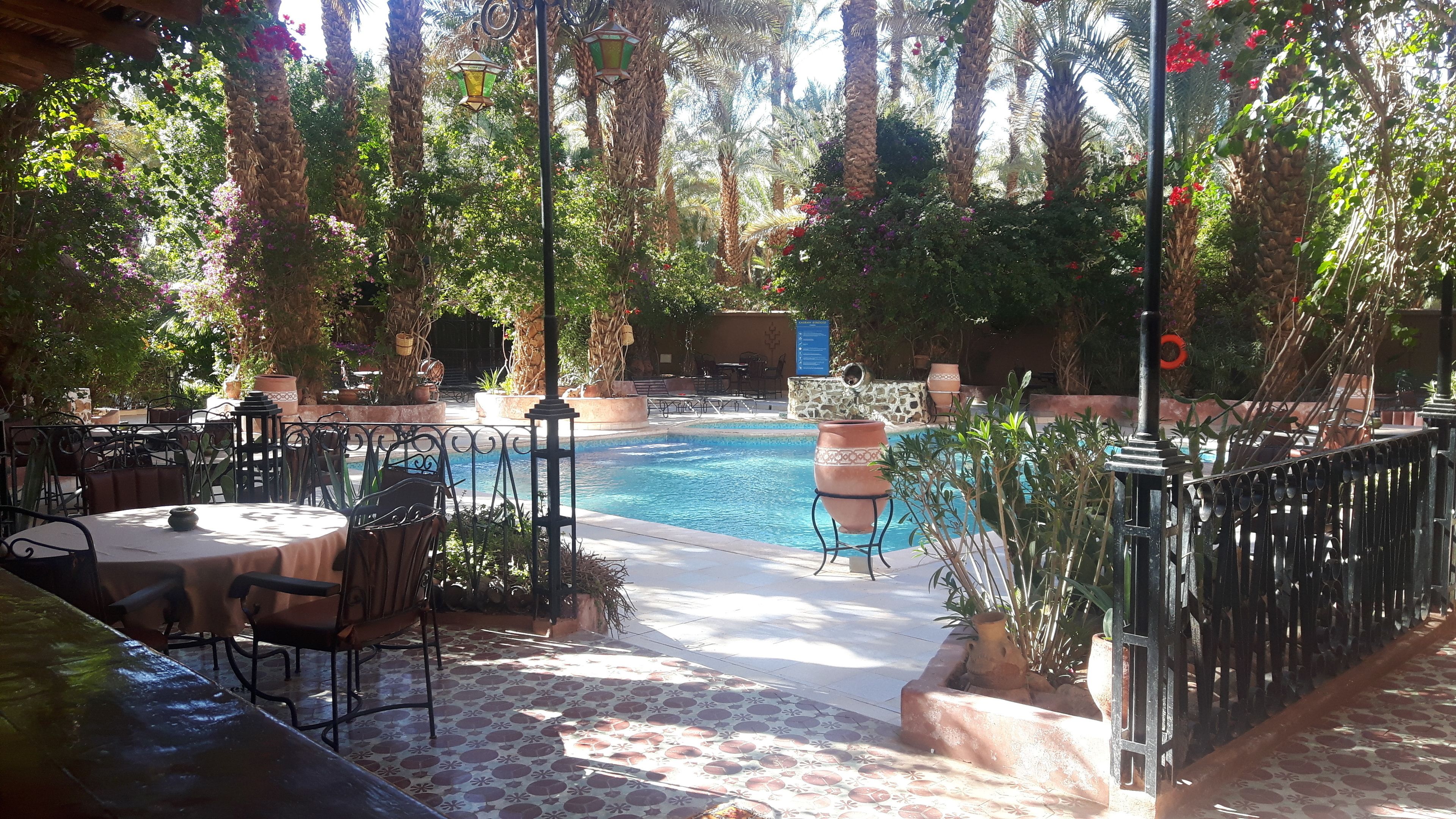 Zona junto a la piscina con un patio empedrado, mobiliario exterior y un muro de piedra.