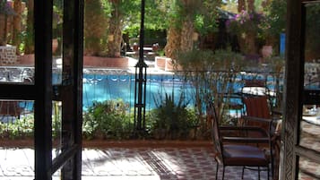 Eine Außenpatio mit Pool, umgeben von Palmen und einer Pergola.