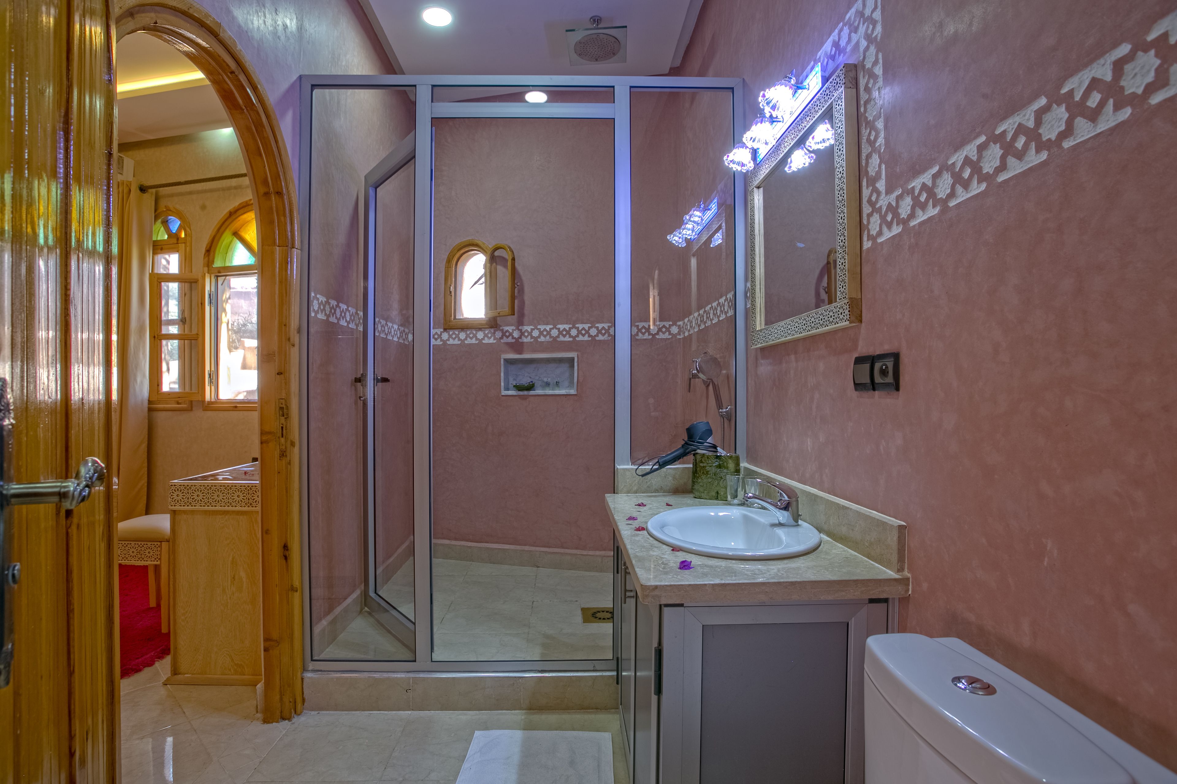 A bathroom with a glass shower enclosure, a sink with a mirror, and a toilet.
