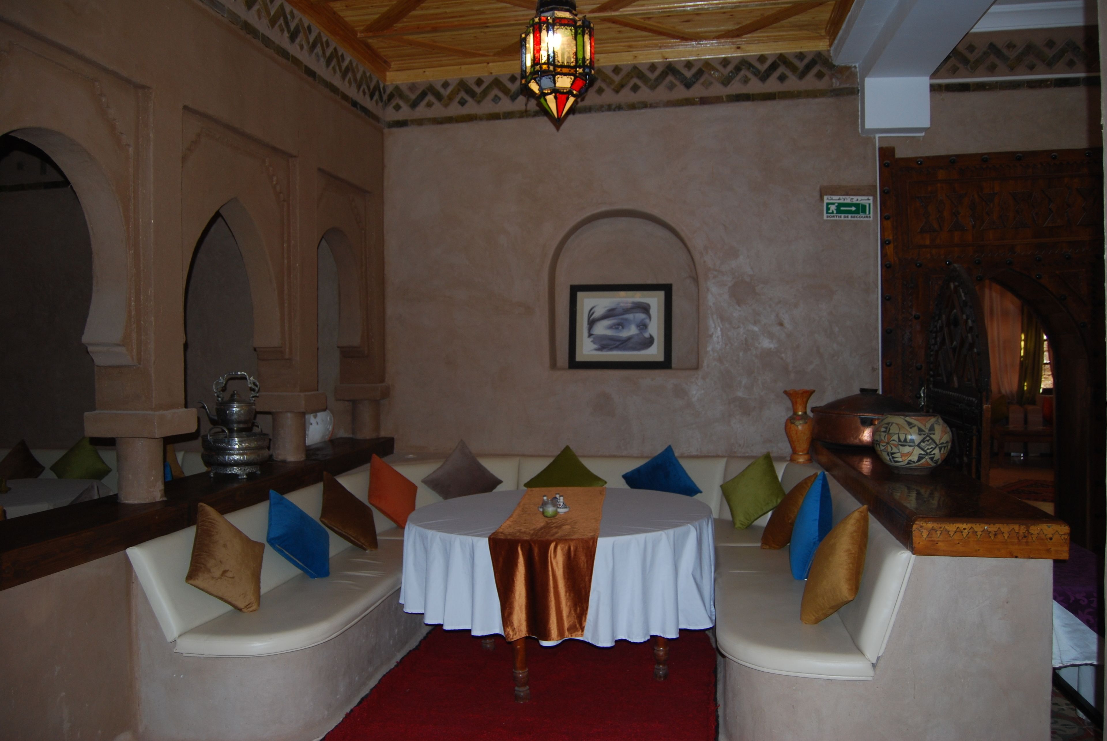 Una zona de estar acogedora con bancos acolchados, una mesa con mantel y una pared decorativa con un cuadro enmarcado.