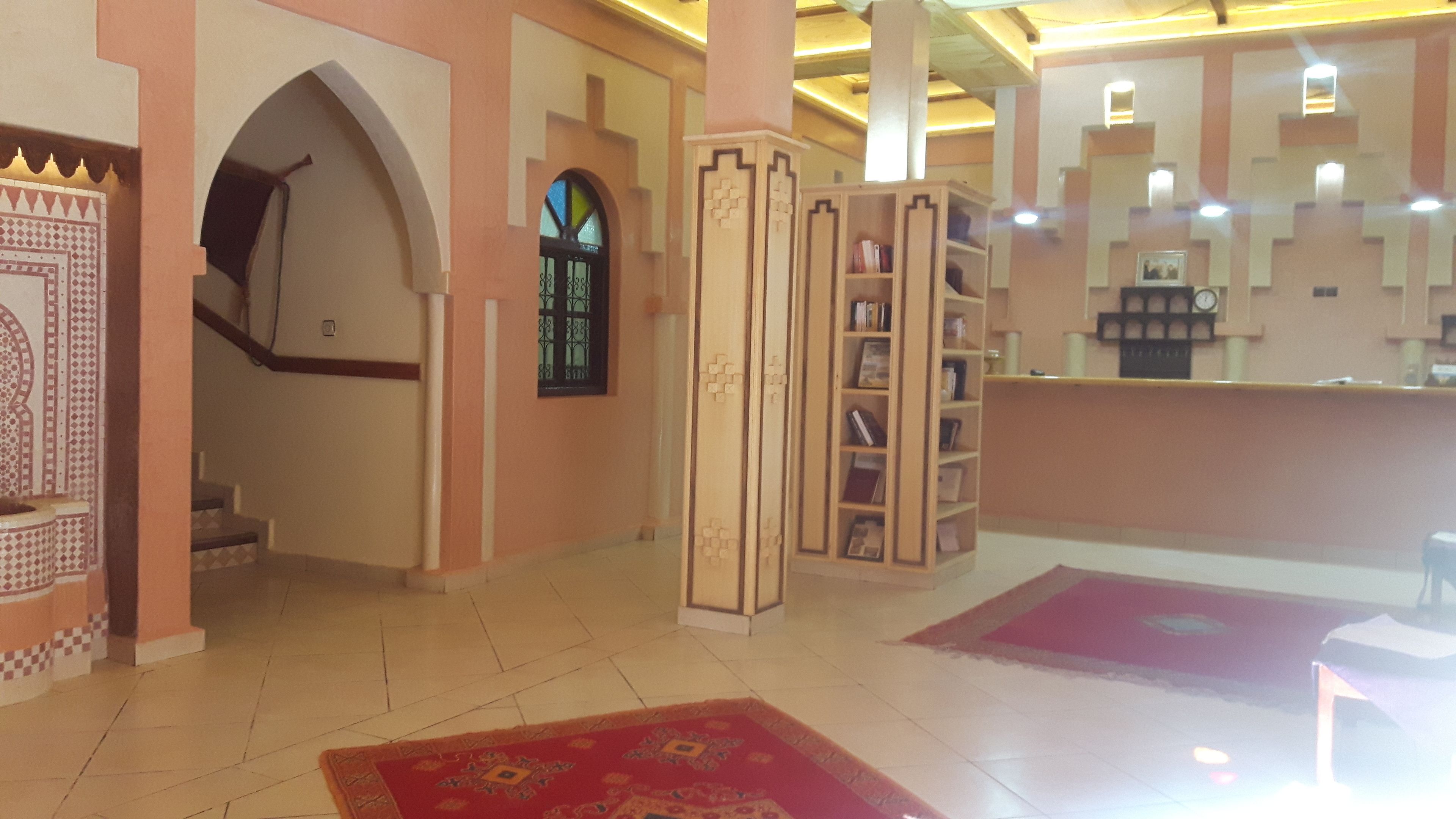 Un hall d’entrée avec un escalier, un comptoir de réception et une bibliothèque.