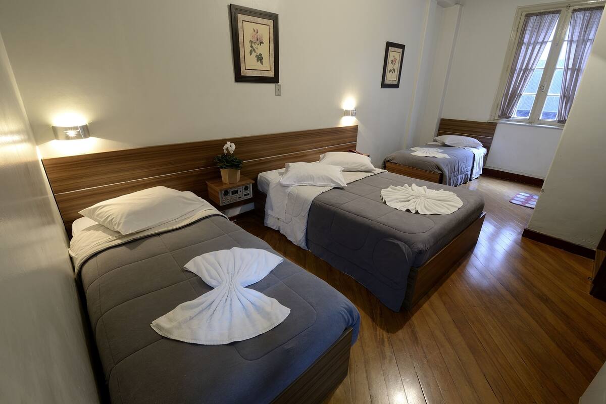 Ein Hotelzimmer mit zwei Betten, Holzboden und Wandleuchten.