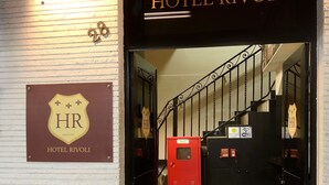 La entrada al Hotel Rivoli, con un letrero sobre la puerta, un felpudo con el nombre del hotel y una escalera que da al interior.