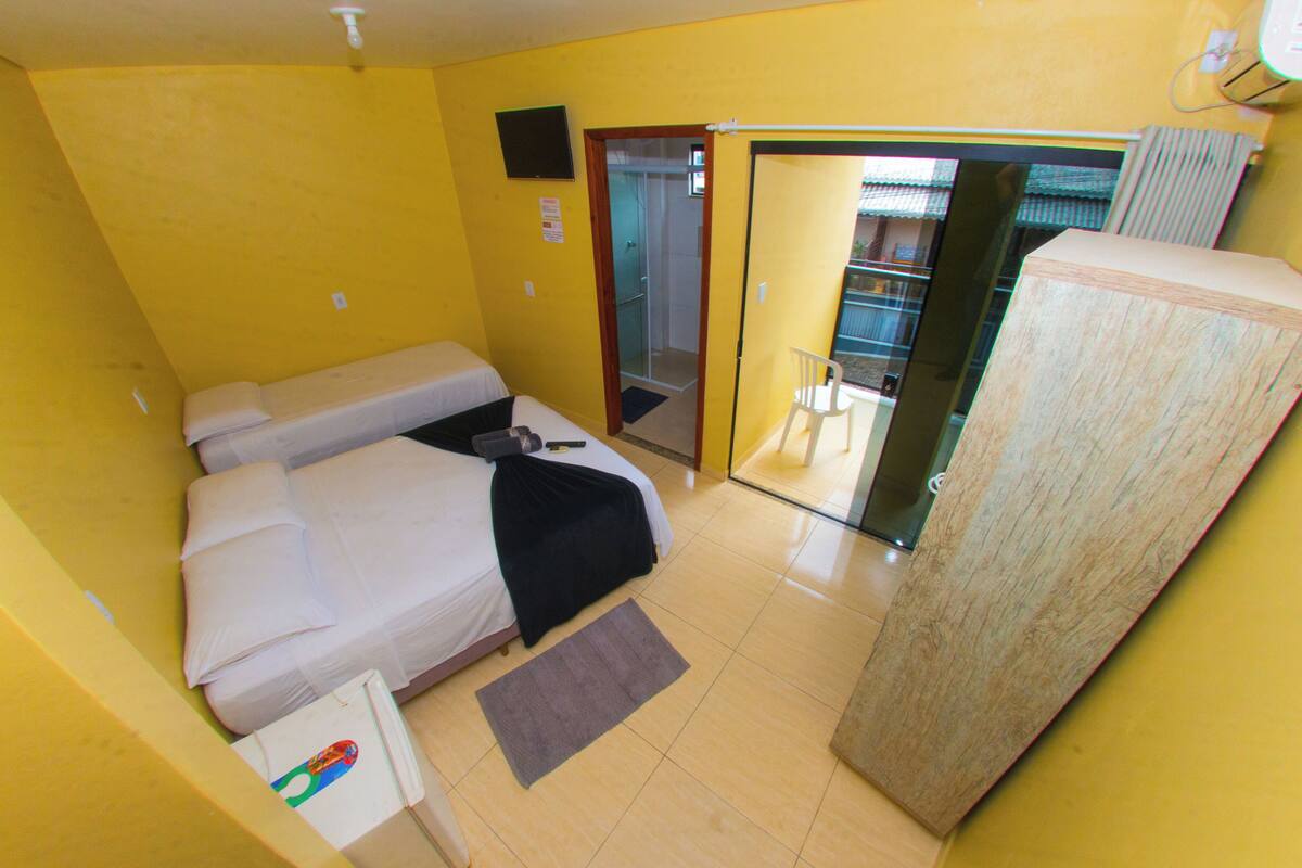 A compact hotel room with a bed, a small desk, a chair, and a wardrobe.