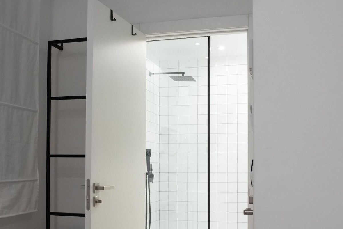 Ein modernes Badezimmer mit Duschkabine aus Glas, einer weißen Toilette und einem Handtuchhalter.