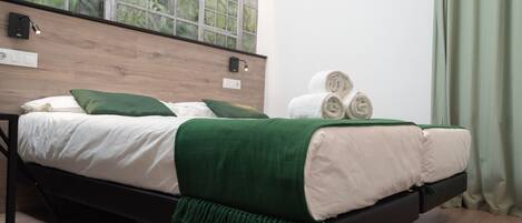 A bed with white and green bedding, a wooden headboard, and a window with a view of greenery.