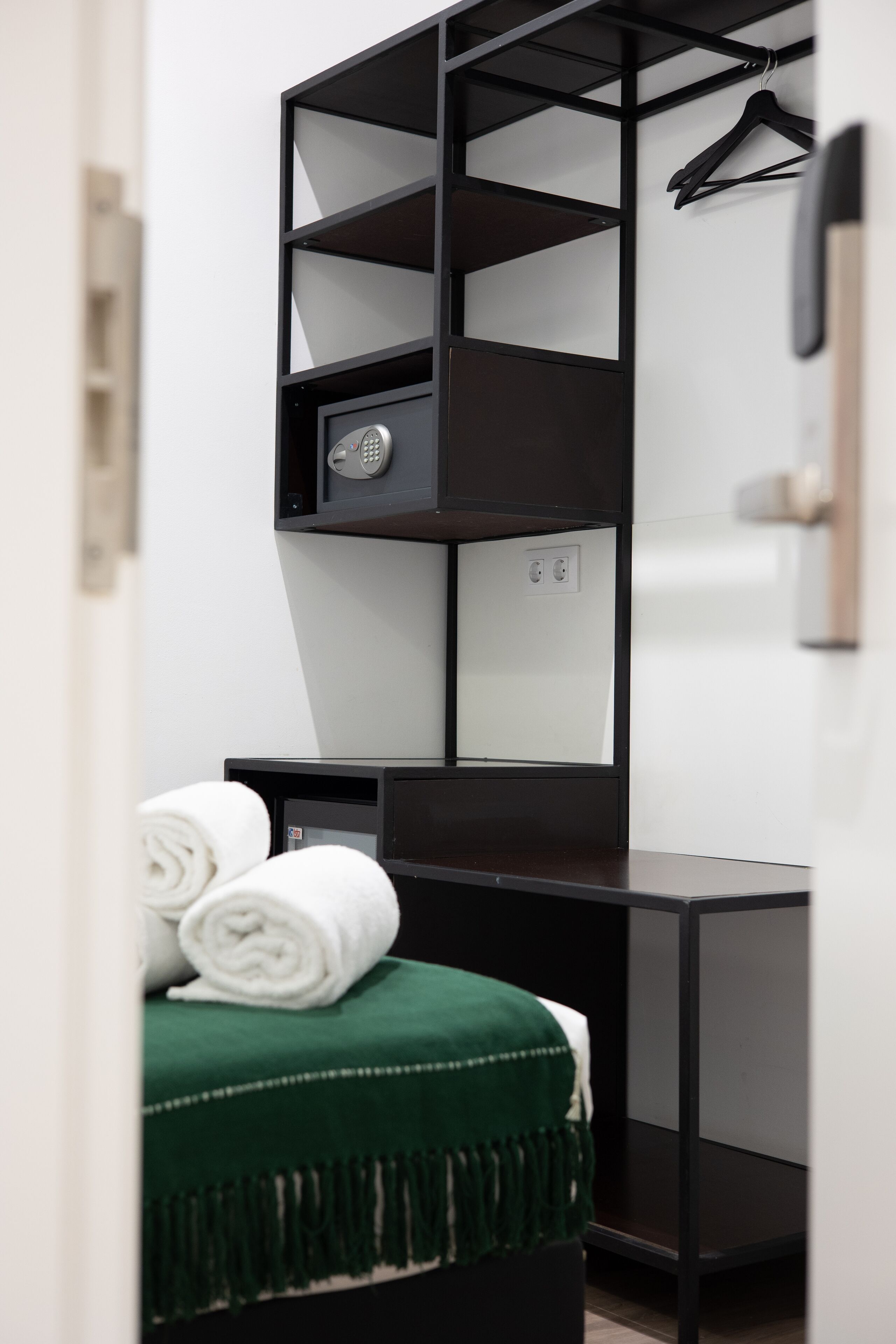 Une chambre d’hôtel de taille réduite, comprenant un lit, un bureau et une armoire.