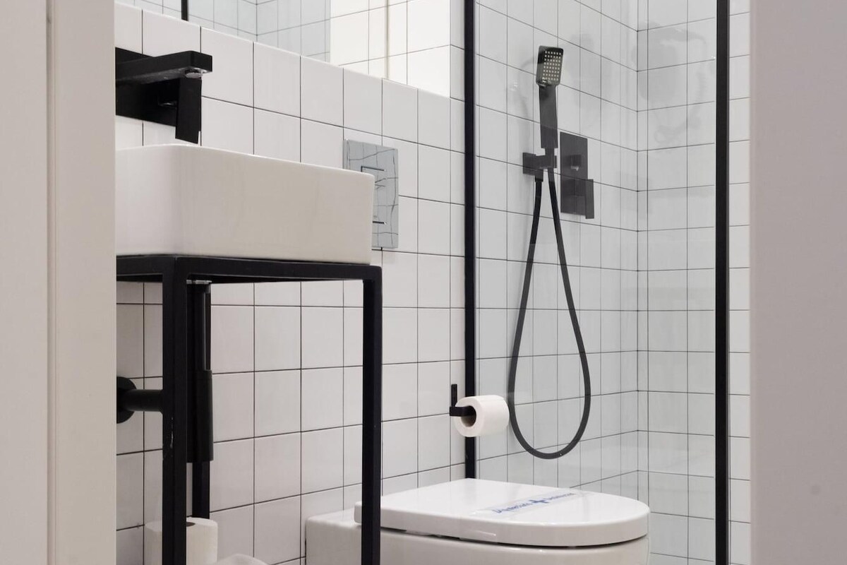 A modern bathroom with a freestanding bathtub, a glass shower enclosure, and a black-framed vanity with a towel rack.