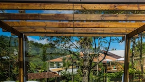 A wooden deck with a hot tub and lounge chairs, overlooking a lush garden and houses.