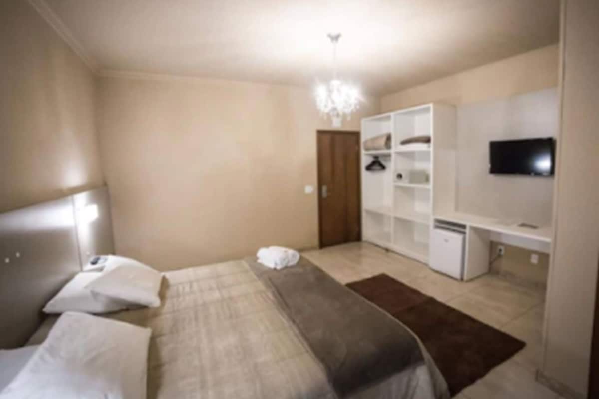 Un dormitorio con cama, armario, televisor y escritorio.